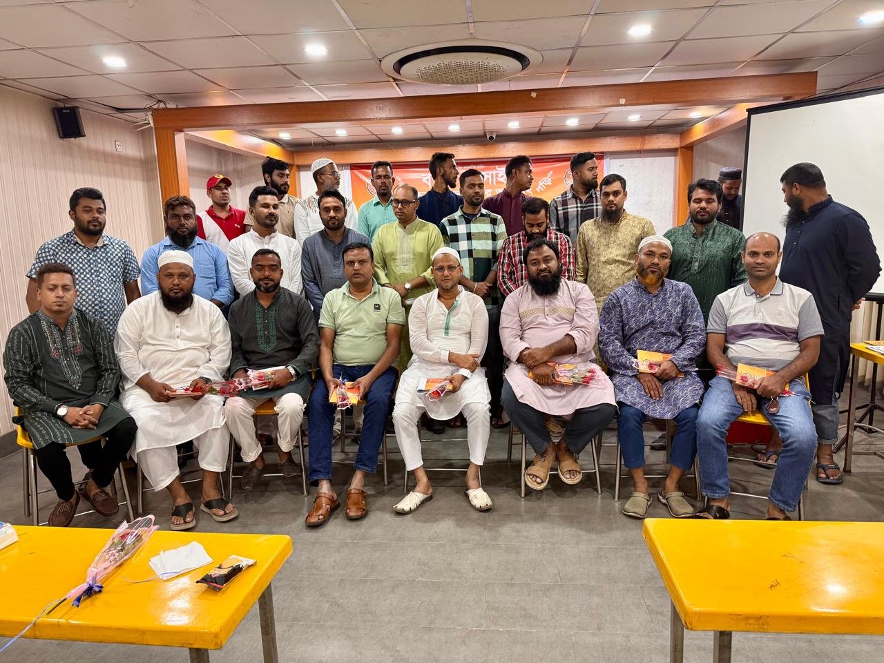 সভাকক্ষে একসঙ্গে বসে ও দাঁড়িয়ে থাকা অংশগ্রহণকারীরা।